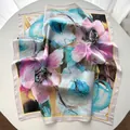 Close-up of abstract oil painting floral silk scarf with elegant folds on white table - Khaki