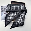 Close-up of elegant houndstooth silk scarf with geometric star patterns on a gold tray - Black