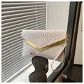 Close-up of white crocodile pattern envelope clutch bag with V-shaped gold metal trim - White