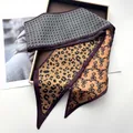 Detail eines Seidenschals mit Leopardenmuster und Karomuster in einer Geschenkbox - Zitronengelb