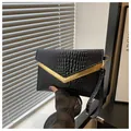 Close-up of black crocodile pattern clutch bag with golden V-shaped metal hardware - Black