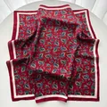 Carré de soie rouge élégant avec motifs paisley bleus et jaunes sur une table blanche - Rouge