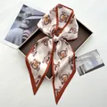 Elegant silk satin scarf with unicorn badge pattern displayed as a bow on a vintage tray - Off-White with Caramel Trim Unicorn Style (Style 11)