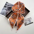 Orange silk satin twilly scarf with chain fringe print tied in a bow on a display tray - Vibrant Orange Chain Tassel Retro Style (Style 16)