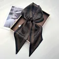 Elegant black and gold U-pattern satin scarf tied in a bow on a luxury leather tray - Black