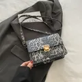 Fashionable dark grey leopard print crossbody bag with gold buckle on blazer background - Black