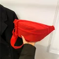 Sporty bright red nylon sling bag with woven rope zipper detail held by model - Red