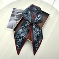 Navy blue paisley print twilly scarf tied in a bow on a gold decorative tray - Navy Blue Paisley with Red-Brown Border (Style 36)