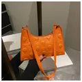 Detailed close-up of orange underarm bag featuring distinctive scale embossed PU leather - Orange