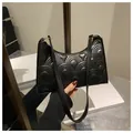 Detailed view of black underarm bag featuring fan-shaped quilting and gold hardware - Black