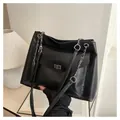Detail van een zwarte leren shopper met metalen draaisluiting en ketting schouderriem - Zwart