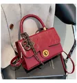 Détail d'un sac à main en cuir verni bordeaux avec fermoir doré et breloque tissée - Sans pendentif / Rouge