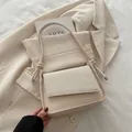 Minimalist beige shoulder bag featuring woven flap design and smooth leather texture - Off White