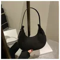 Detalle de bolso hobo de ante negro con líneas fluidas y herrajes plateados de lujo - Negro