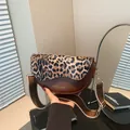 Borsa a sella leopardata in pelle marrone con ampia tracolla in un ambiente alla moda - Leopardo Marrone