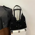 Large black velvet shoulder bag with gold studs and pearls on a white suitcase - Black