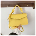 Detail of yellow woven square handbag with knotted handle and envelope flap design - Yellow