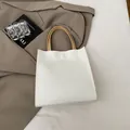 Minimalist white tote bag with light brown handles on a khaki suit background - White