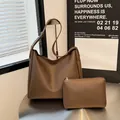 Minimalistische bruine lederen tote bag set met bijpassende binnentas op metalen tafel - koffiekleur