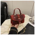 Detail van rode mini-tas met slangenpatroon, gouden ketting en metalen sluiting - Rood