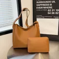 Brown vintage faux leather tote and matching zipper pouch set for women on metal table - Yellow Brown
