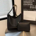 Minimalist black tote bag and matching zippered pouch on a modern metal desk - Black