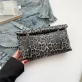Chique handtas met donkere luipaardprint en gouden details vastgehouden door vrouw - Zwart