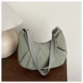 Detail of green pleated nylon crescent bag on wooden table with a soft lamp background - Green