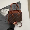 Bolso tote marrón con diseño de monograma, letras doradas y correa de hombro ajustable - café