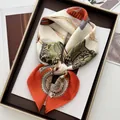 Detail of silk scarf with vintage equestrian chain pattern displayed in a brown tray - Orange Red
