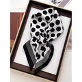 Elegant black and white polka dot silk scarf with striped edges folded in a tray - Black