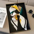 Modern geometric silk scarf with yellow and green color block design on a black tray - Black