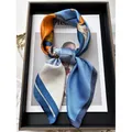 Modern abstract floral satin twilly scarf in orange and blue tied on a fashion magazine - Blue