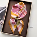 Detailed top view of silk scarf with abstract floral patterns in a metal tray - Dark Brown