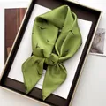 Macro detail of grass green satin silk scarf with black seagull print tied in a bow - Light Green