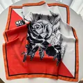 Detalle del pañuelo cuadrado de satén de seda con motivos florales naranjas y negros - 65cm x 65cm / Rojo Anaranjado