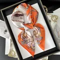 Retro silk square scarf featuring orange chain pattern tied in a bow on a luxury tray - Orange