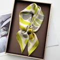 Detail of geometric pattern silk scarf presented in an elegant brown rectangle gift box - Green