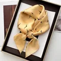 Detail view of yellow silk square scarf with black bird print tied in a decorative knot - Lemon Yellow