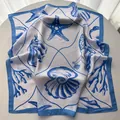 Detail of silk-like square scarf featuring blue starfish and seashell ocean patterns - Blue