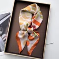 Detail of silk-feel scarf with geometric paisley patterns in a luxury gold-rimmed gift box - Orange Red