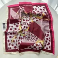 Carré de soie bordeaux à pois avec motifs de chaînes dorées sur table blanche - Rose
