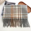 Vue détaillée d'une écharpe à carreaux bicolore avec pompons en marron et gris - Gris