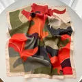 Close-up of printed silk square scarf with floral pattern and high-gloss satin texture - Orange