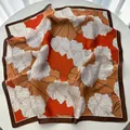 Détail d'un foulard en soie à imprimé floral orange et bordure marron sur table blanche - Orange Blanc Brun Floral (25)