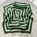 Detailed view of striped green and white silk scarf with soft fabric texture and glossy finish - Green