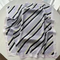 Close-up of a striped silk square scarf with purple and navy bands on a white surface - Lavender