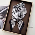 Detalle de pañuelo de seda con estampado de cuadros clásicos en una elegante caja de regalo - Negro