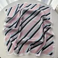 Detail of a square silk scarf with pastel stripes and premium satin texture on display - Pink