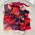 Detailed view of the abstract geometric pattern silk scarf with soft satin texture - Red